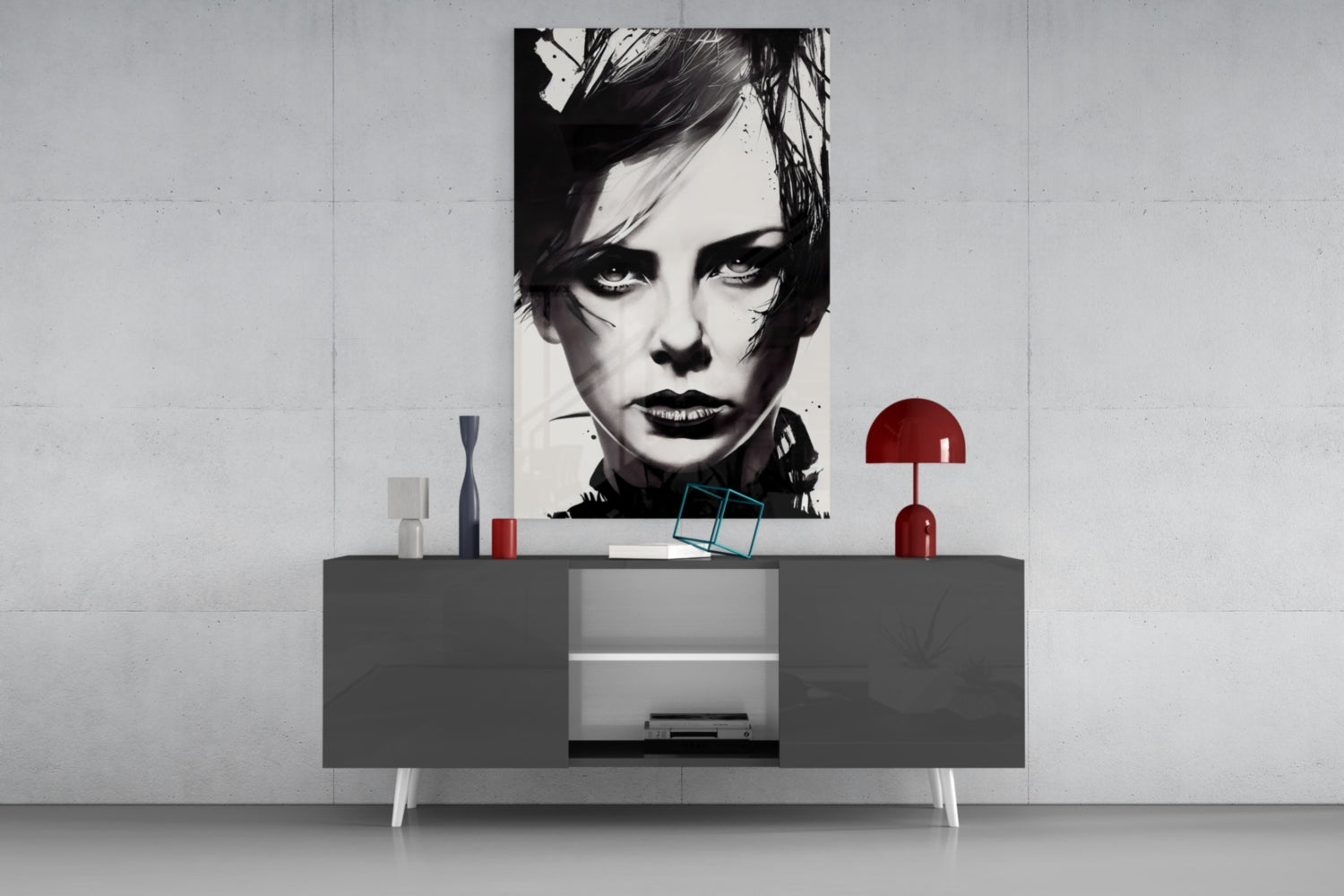 Black and white portrait glass wall art displayed above gray modern credenza with red lamp and decorative objects.