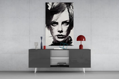 Black and white portrait glass wall art displayed above gray modern credenza with red lamp and decorative objects.