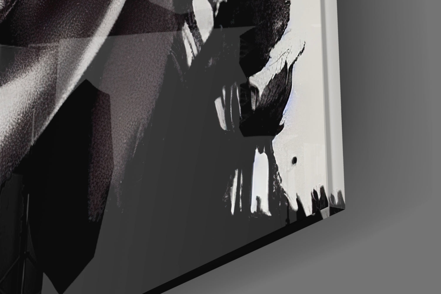 Close-up detail of black and white abstract brushstroke design on glass surface with gray wall reflection.