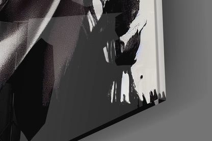 Close-up detail of black and white abstract brushstroke design on glass surface with gray wall reflection.