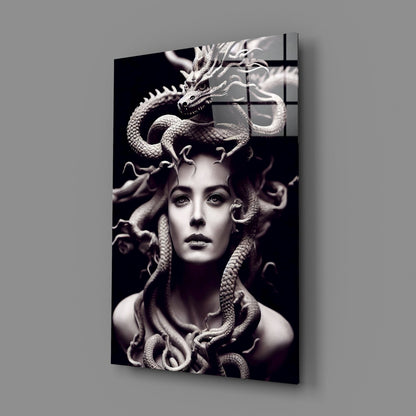 Glass art panel displaying a monochromatic portrait of a woman with serpents coiled around her head and neck, mounted at an angle against grey background.