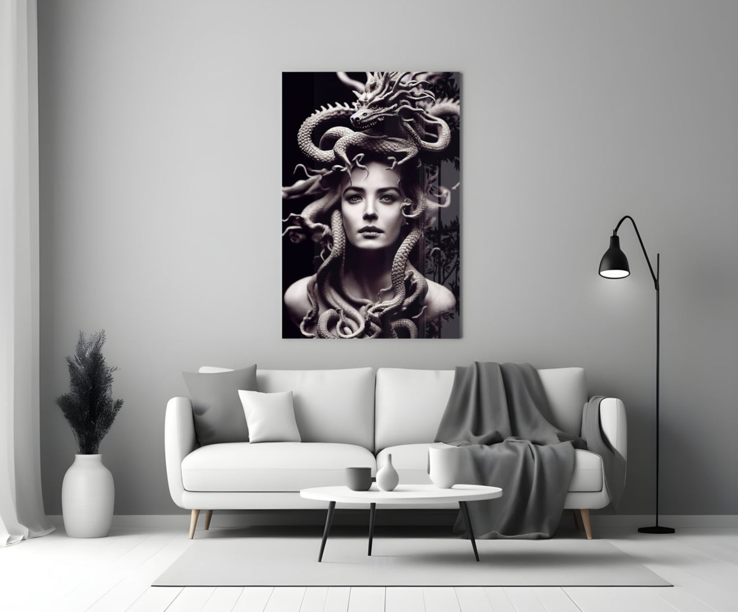 Monochrome glass art depicting a woman with serpents in her hair, displayed above a white sofa in a modern living room.