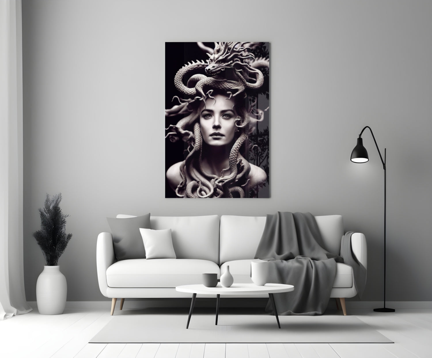 Monochrome glass art depicting a woman with serpents in her hair, displayed above a white sofa in a modern living room.