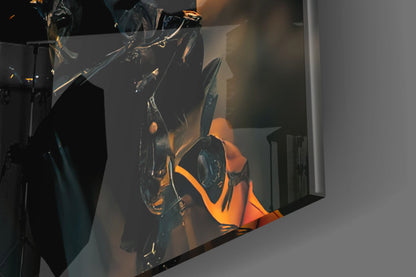 Close-up of black glass art sculpture with orange and gold accents illuminated against white gallery wall.