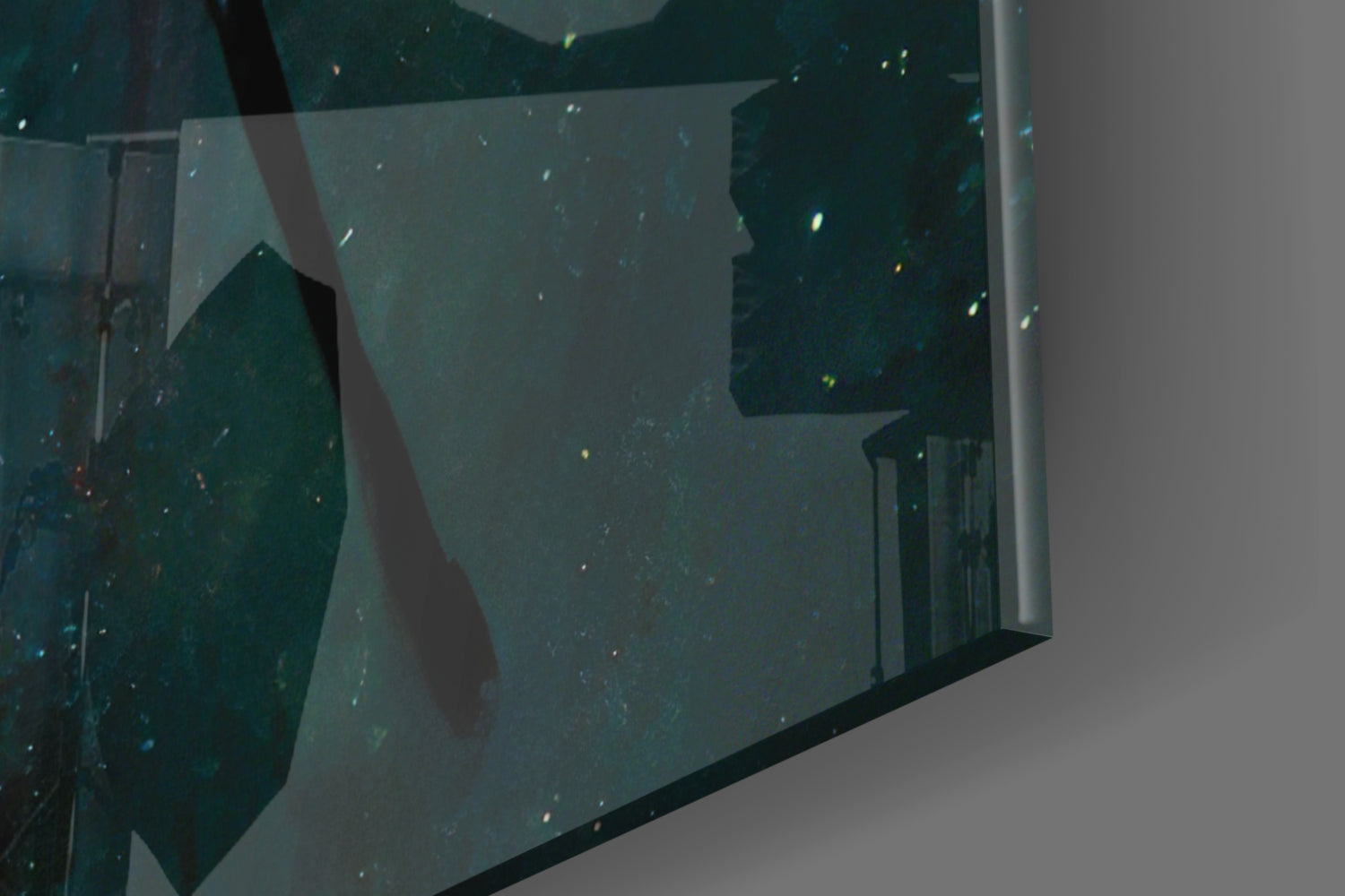 Close-up angled view of teal and dark green glass wall art panel with gold leaf accents and visible frame edge against white background.