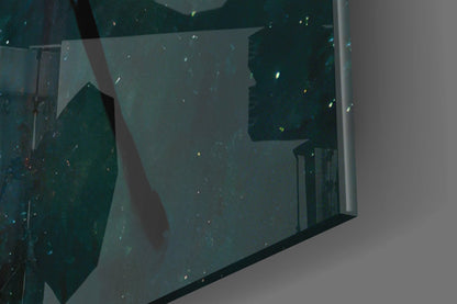 Close-up angled view of teal and dark green glass wall art panel with gold leaf accents and visible frame edge against white background.