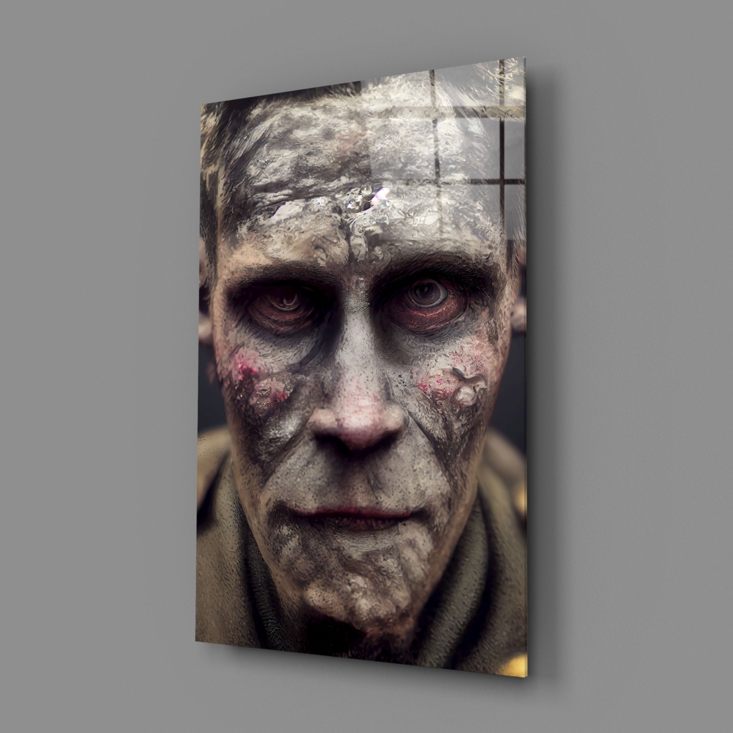 Decayed Glass Art canvas displaying a close-up frontal portrait of a weathered face with pale grey texture, dark hollowed eyes, and pink blemishes, mounted on gray wall.