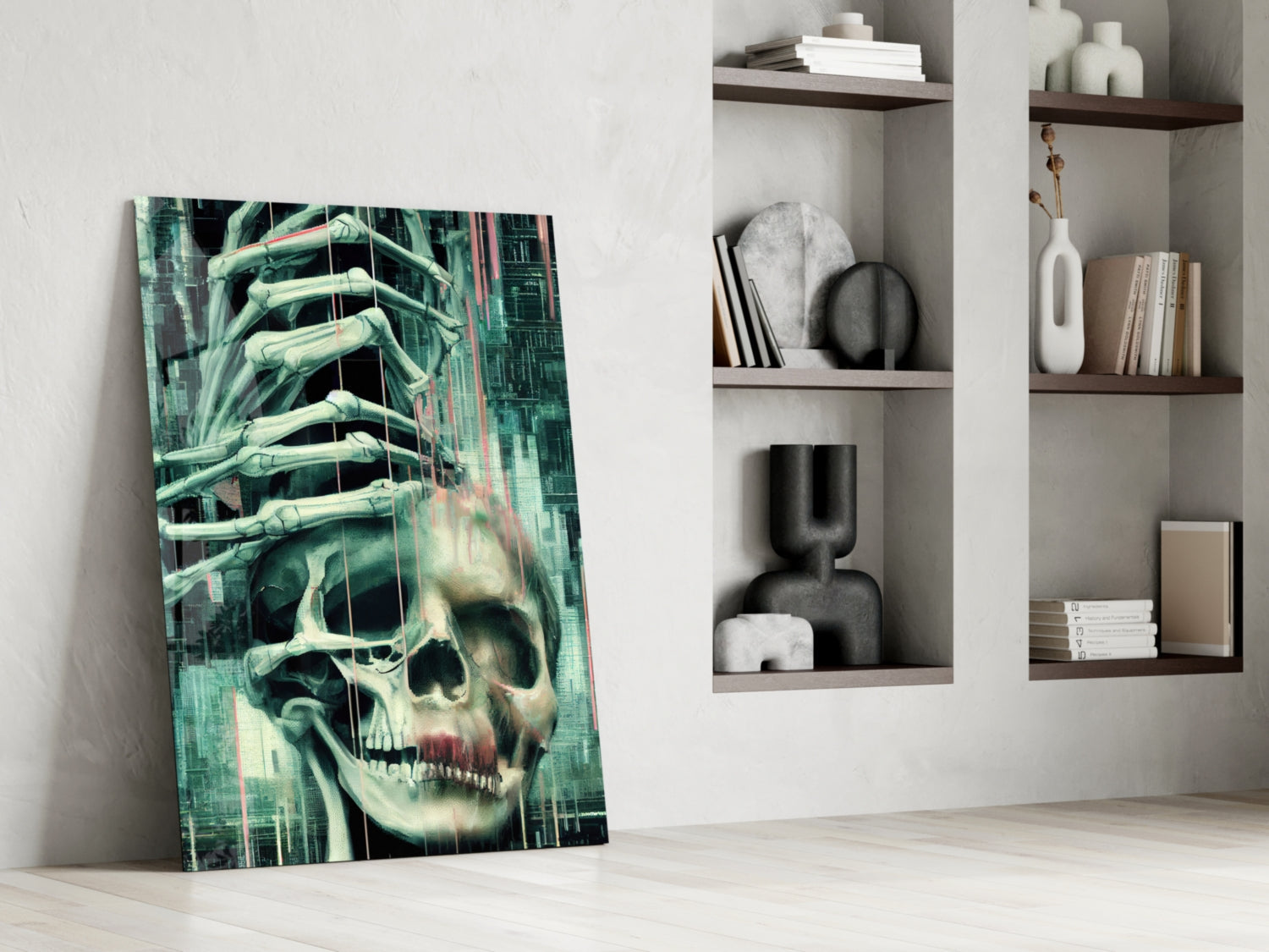 Glass art panel leaning against white wall beside shelving unit, depicting skull with skeletal hands in green and cream tones.