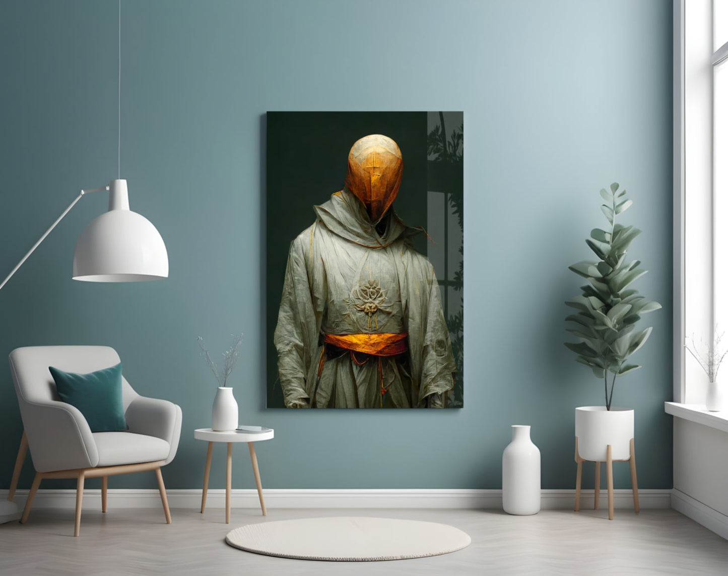 Headless Monk glass art displayed on teal wall above white chair, showing golden spherical head and cream robe with orange sash.