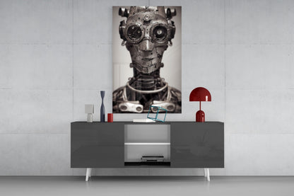Steampunk mechanical head portrait with brass goggles displayed on wall above modern gray console table with red lamp and decorative objects.
