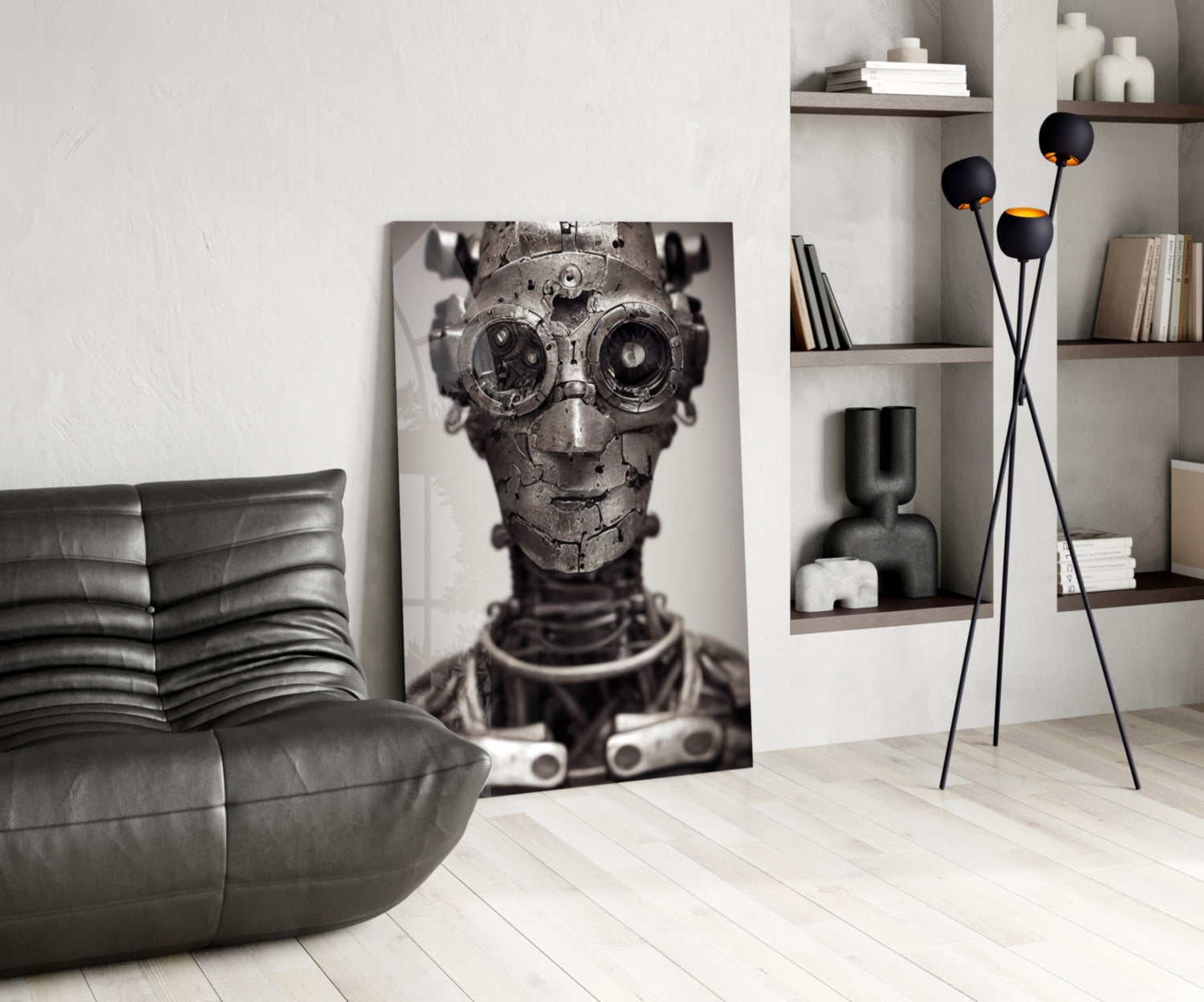 Black and white mechanical skull artwork displayed on floor against wall in modern living room with leather chair and shelving.