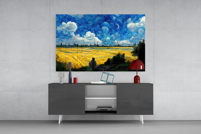 Glass art print depicting a golden wheat field under blue sky with white clouds, displayed above a dark gray media console in a modern interior setting.