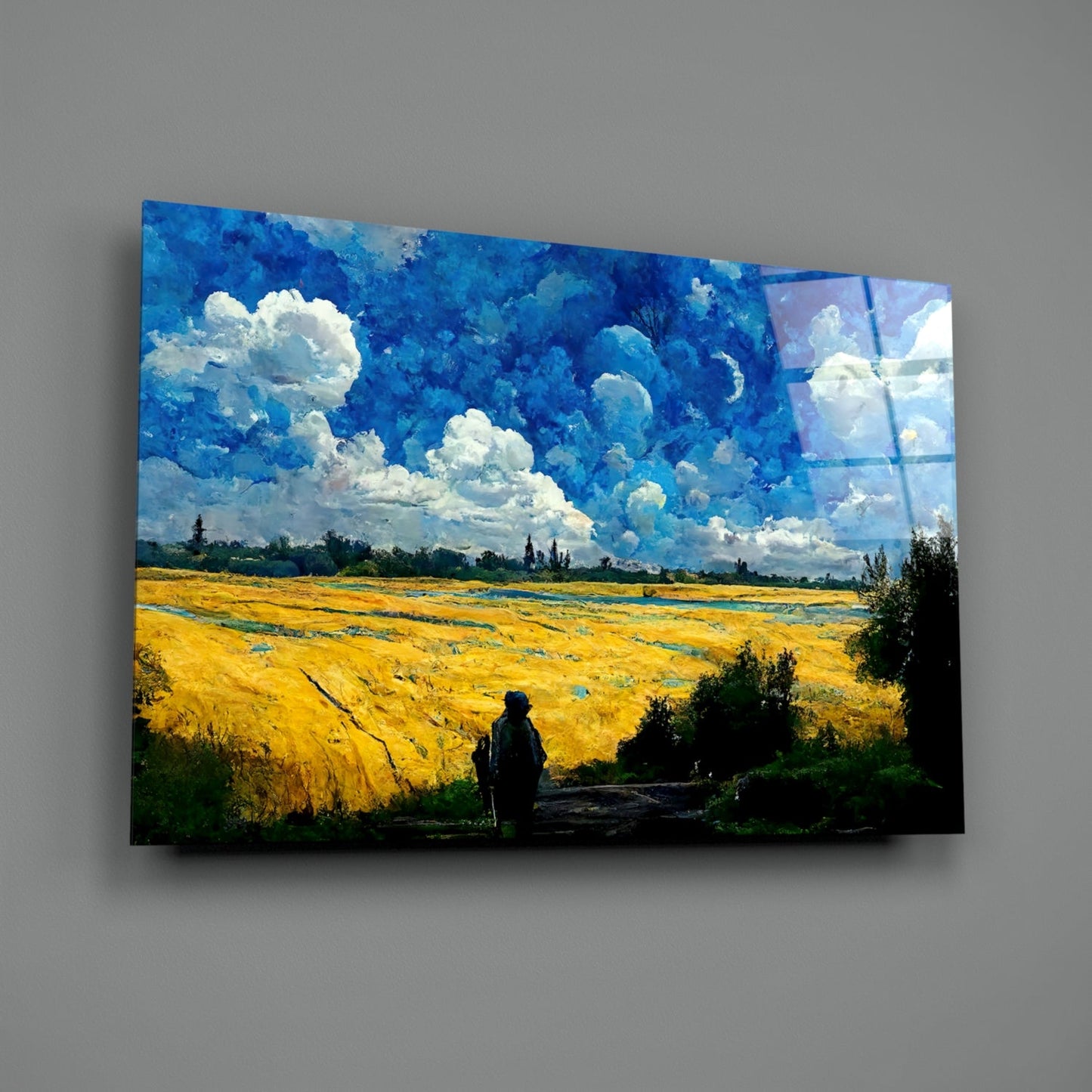 Glass art panel mounted on gray wall showing a solitary figure overlooking a golden wheat field beneath a dramatic blue sky with white clouds.