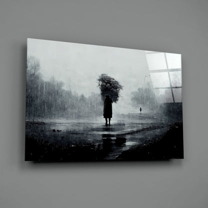 A solitary figure with an umbrella stands in a rain-soaked landscape on translucent glass art mounted against a gray wall.
