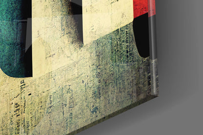 Angled three-dimensional view of glass art piece with cream, green, red, and black color blocks and embossed text on textured surface.