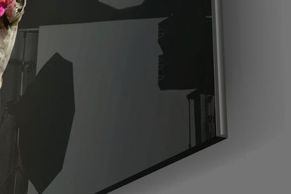 Side view of black glass art sculpture with silhouetted figure against translucent panel, white wall background.