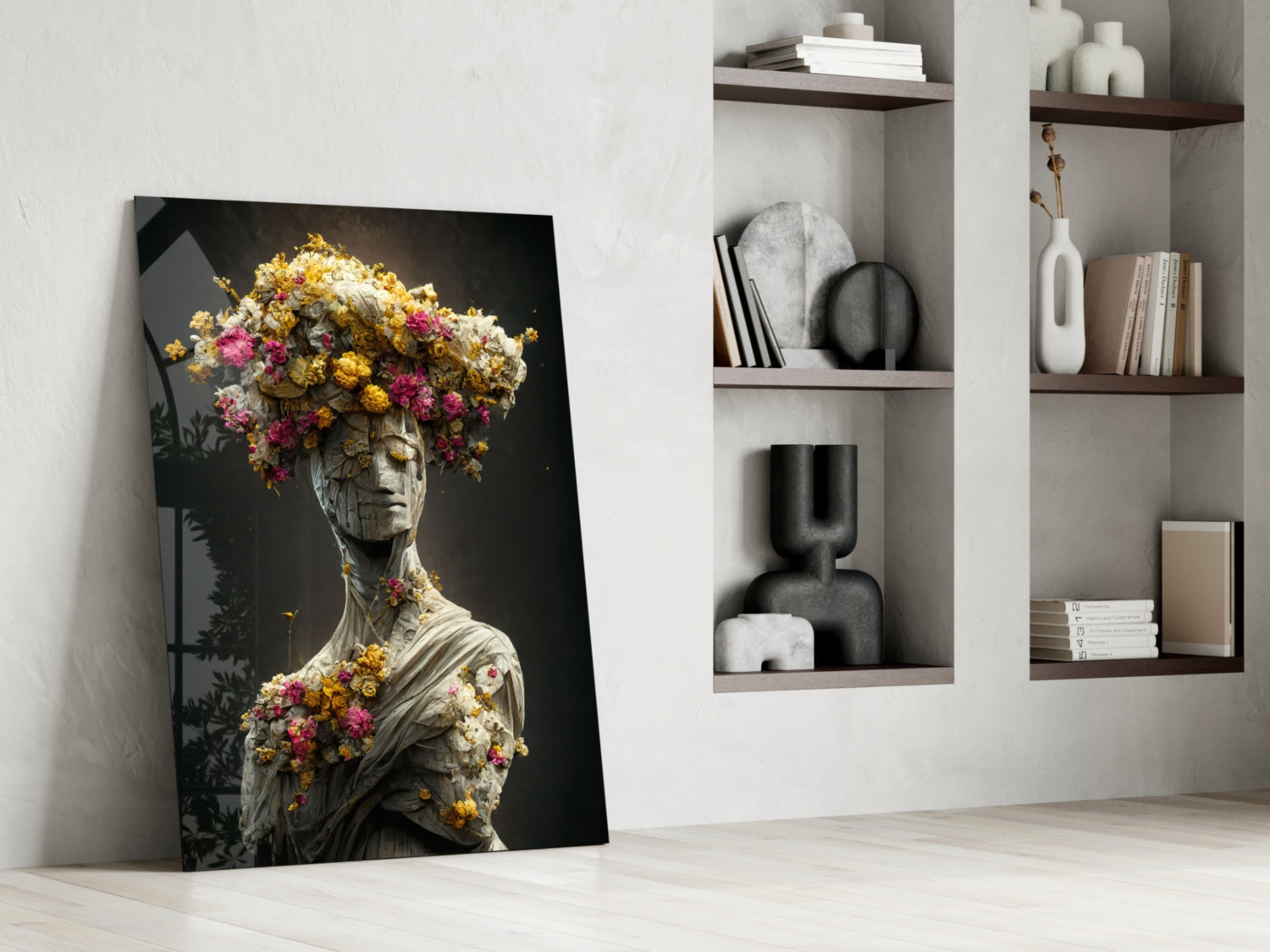 Glass art leaning against white wall shows classical statue bust adorned with yellow, pink, and white flowers on dark background.