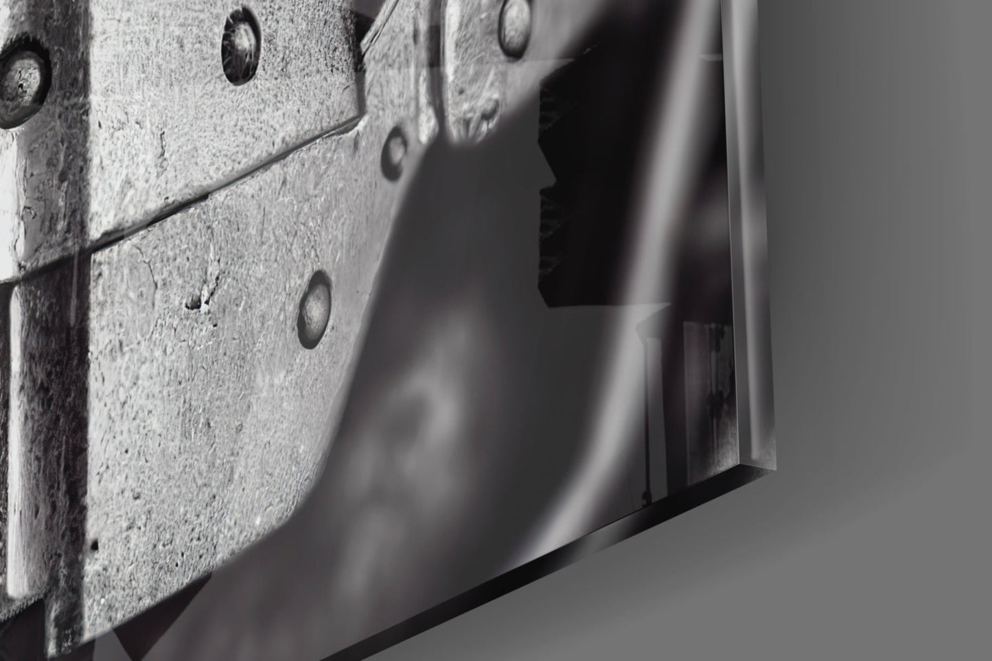 Close-up detail of textured concrete surface with metal rivets and sleek glass edge, monochromatic.