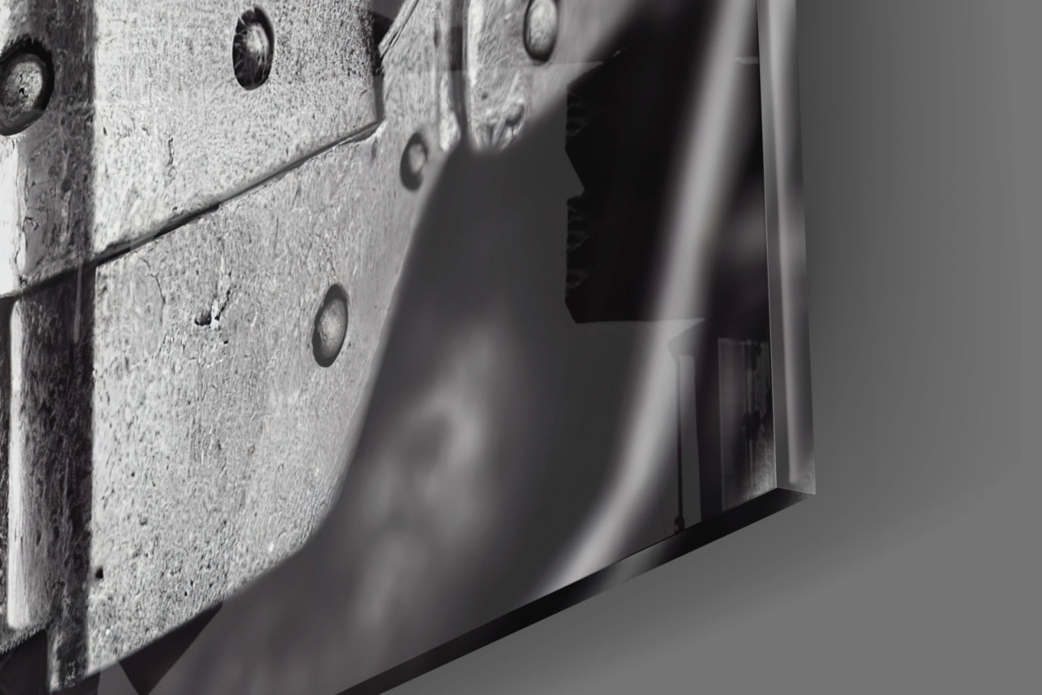 Close-up detail of textured concrete surface with metal rivets and sleek glass edge, monochromatic.
