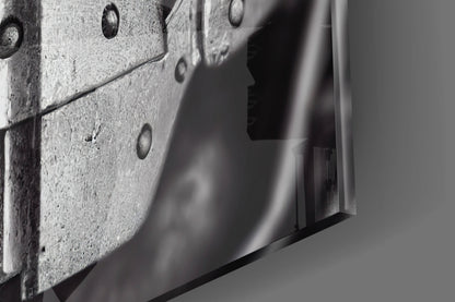 Close-up detail of textured concrete surface with metal rivets and sleek glass edge, monochromatic.