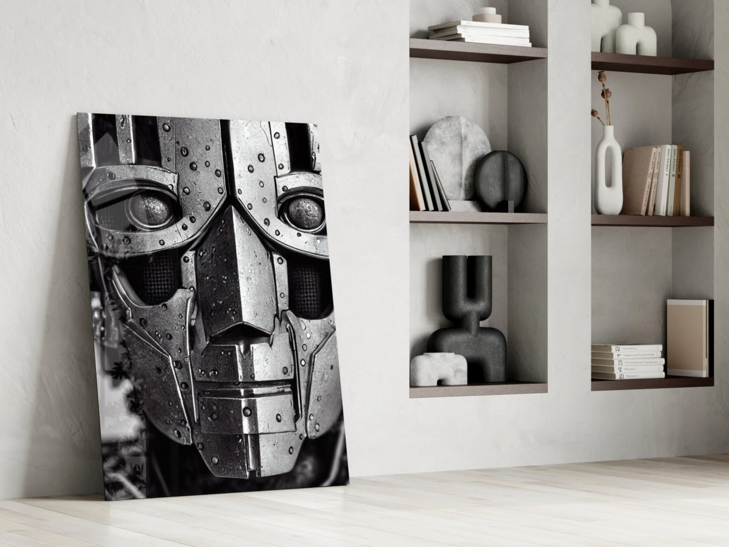 Black and white metallic robotic face canvas leaning against white wall beside wall-mounted shelving with books and decorative objects.