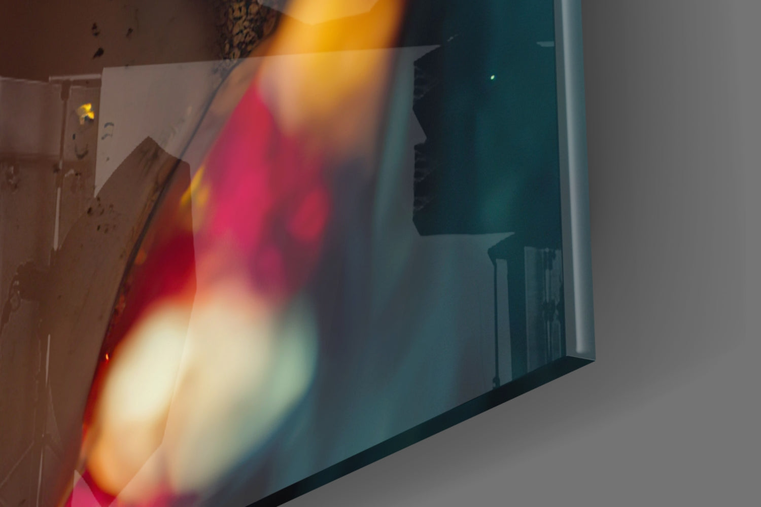 Close-up of translucent glass art piece with vibrant red, yellow, and teal gradient colors and blurred edges, photographed at an angle against neutral background.
