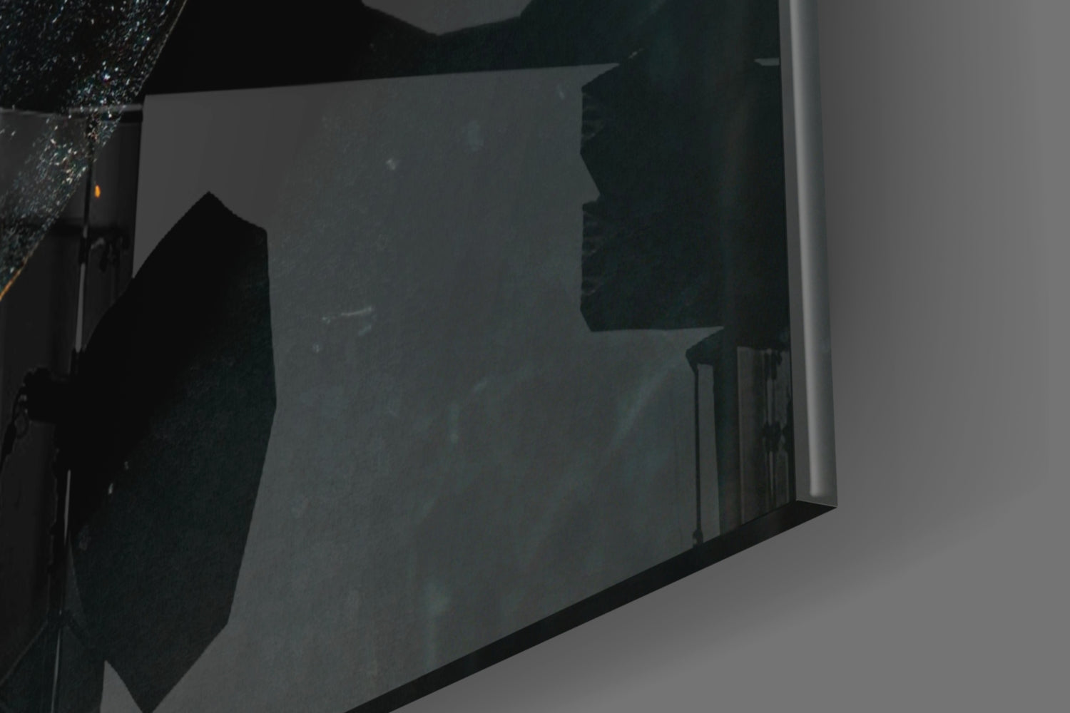 Close-up detail of dark glass art piece showing textured surface and reflective qualities against light background.