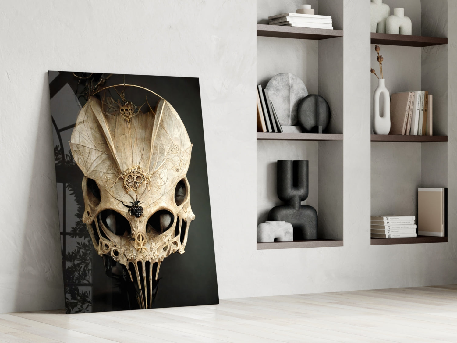Ornate cream and gold skull glass art leaning against white wall beside shelving unit displaying decorative objects.