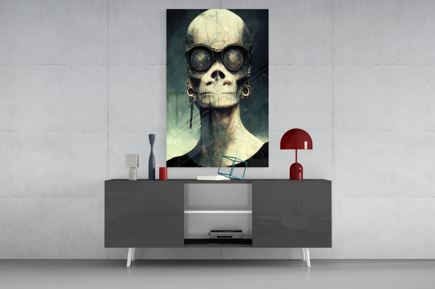 Skull-faced figure wearing steampunk goggles displayed as framed glass art above modern console table with red lamp and decorative objects.