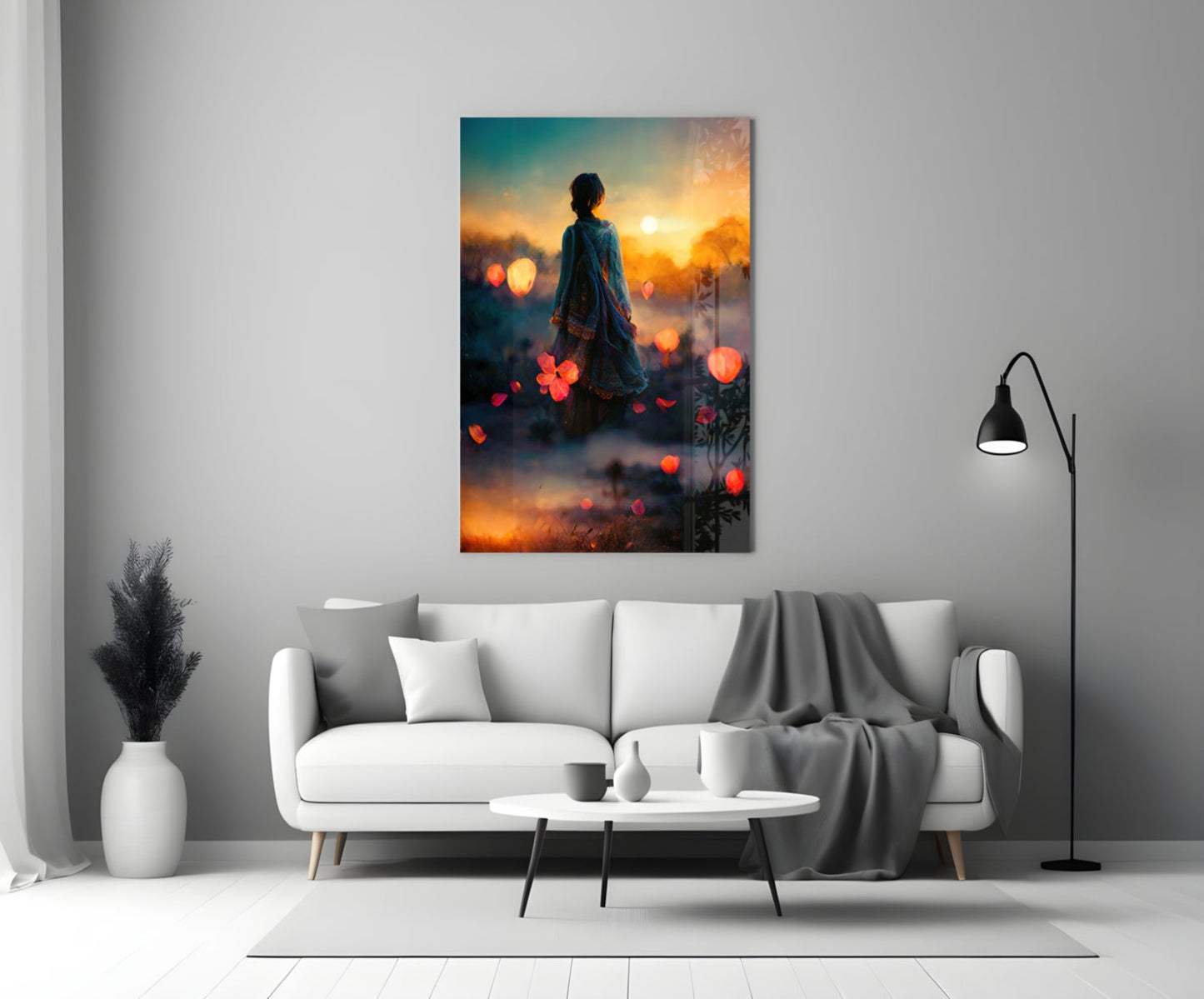 Glass wall art depicting a silhouetted figure at sunset with warm orange and golden bokeh lights against teal sky, displayed above white sofa.