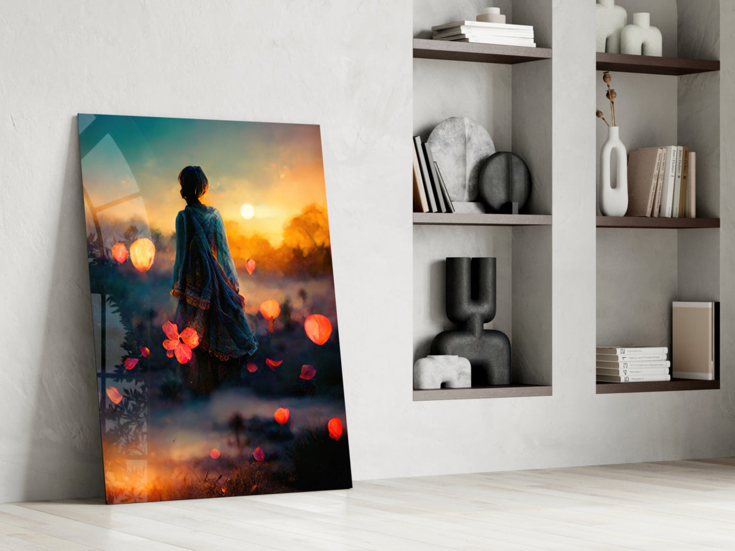 Glass wall art leaning against white wall showing woman in blue clothing facing sunset with glowing orange flowers and bokeh lights.