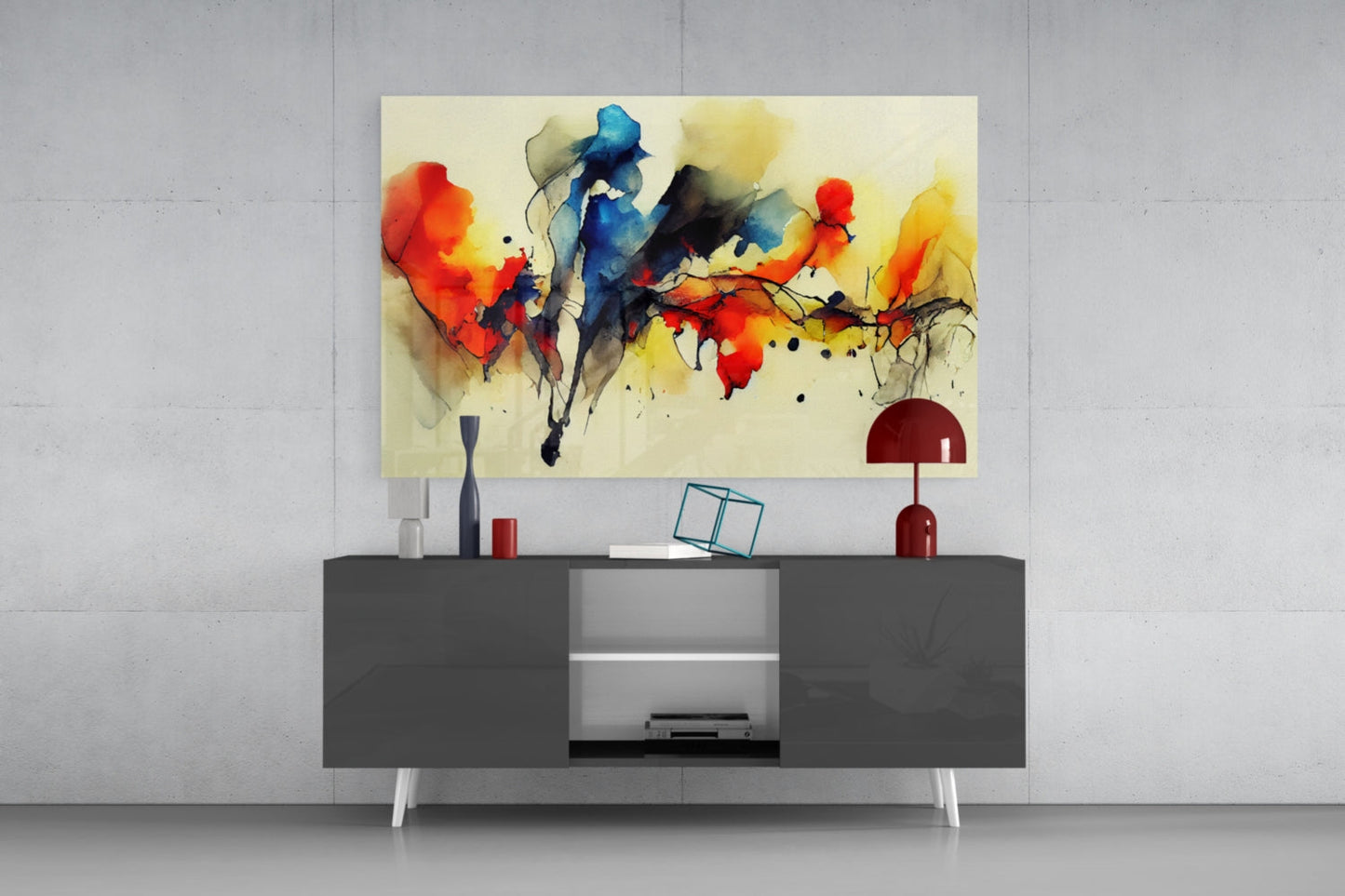Abstract watercolor glass wall art with red, blue, and yellow splashes displayed above a dark gray media console in a modern interior setting.