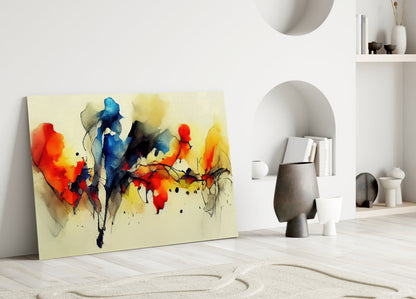 Colorful abstract watercolor glass wall art featuring red, blue, yellow, and black ink splashes on cream background, leaning against white interior wall with shelving.