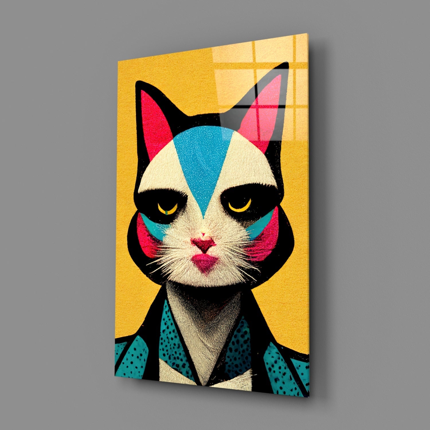 Angled view of a glass wall art panel featuring a stylized cat face with geometric patterns in yellow, teal, pink, and black against a golden background.