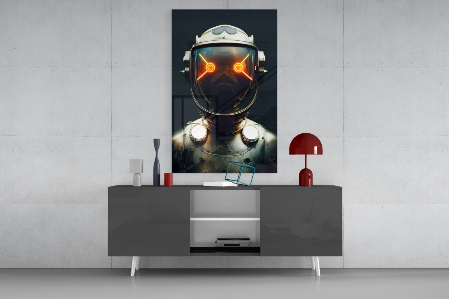 Framed glass wall art displaying glowing orange-eyed robot head mounted above modern gray console table with red lamp and white accessories.