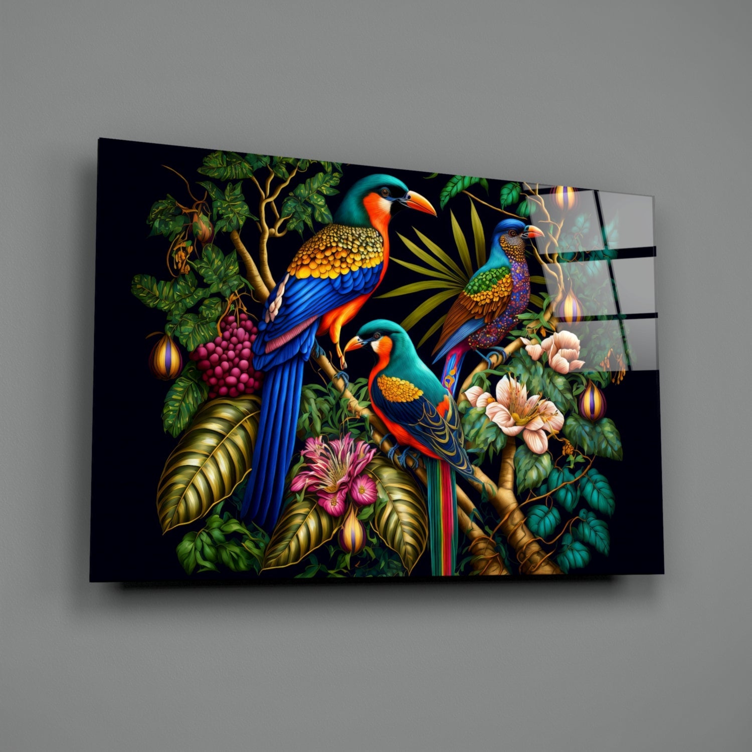 Angled view of glass wall art featuring three colorful parrots perched on branches surrounded by tropical foliage, flowers, and decorative lanterns against a black background.