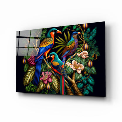 Angled product view of glass wall art featuring three colorful parrots perched among tropical foliage and flowers against a black background.