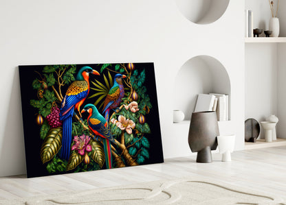 Colorful glass wall art leaning against white wall displays three vibrant parrots with blue, orange, and green plumage among tropical foliage and flowers.