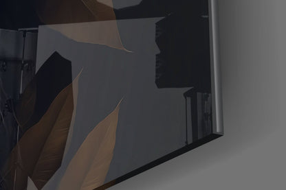 Close-up angled view of glass wall art showing bronze and black leaf designs with light reflection on translucent surface.