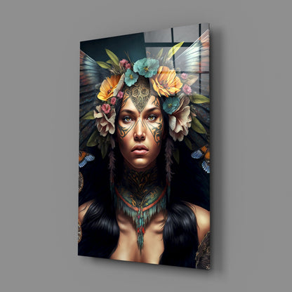 Glass wall art displaying a tattooed figure with facial markings, colorful flowers, and butterfly wings against a dark background.