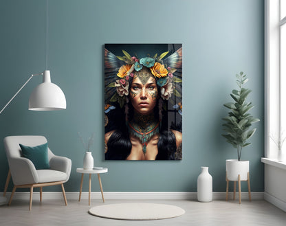 Glass wall art depicting a woman with facial tattoos, floral headdress, and butterfly wings in a styled interior setting.