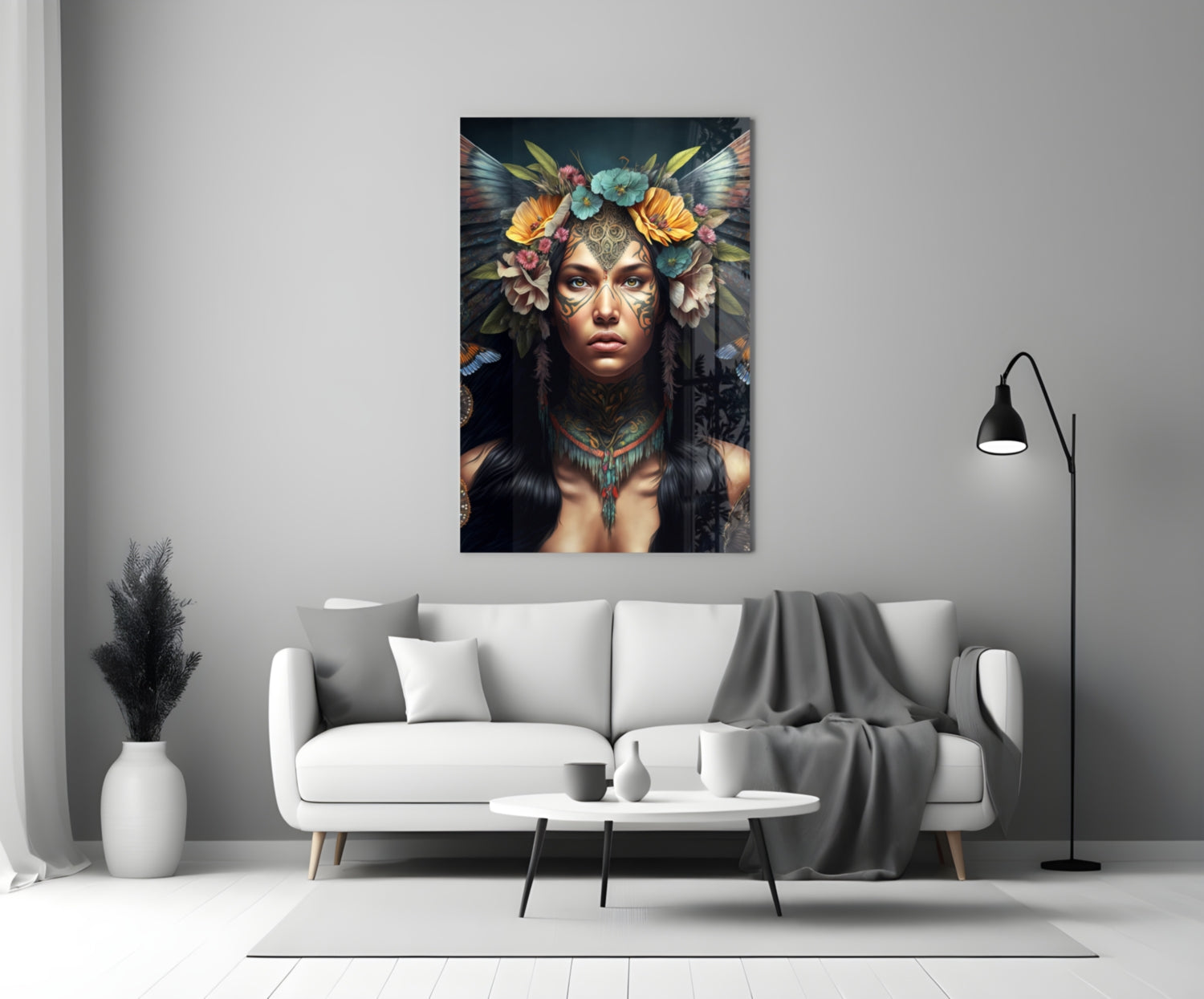 Glass wall art depicting a woman with ornate face paint, colorful flower headdress, and feathered wings displayed above a white sofa.