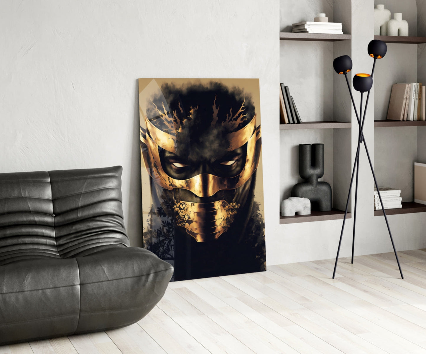 Gold and black masked face artwork displayed in modern living room with gray leather sofa and shelving.
