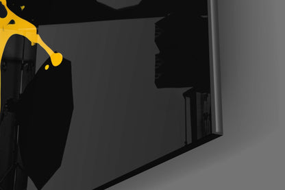 Yellow and black abstract splash glass wall art displayed at an angle in a modern interior space.