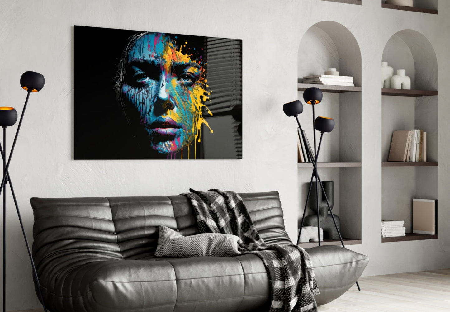 Colorful glass wall art featuring an abstract portrait with blue, yellow, and pink paint splashes displayed above a gray leather sofa in a modern living room.