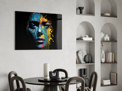 Colorful splash glass wall art featuring a portrait with blue, yellow, and red paint drips displayed above a dining table.