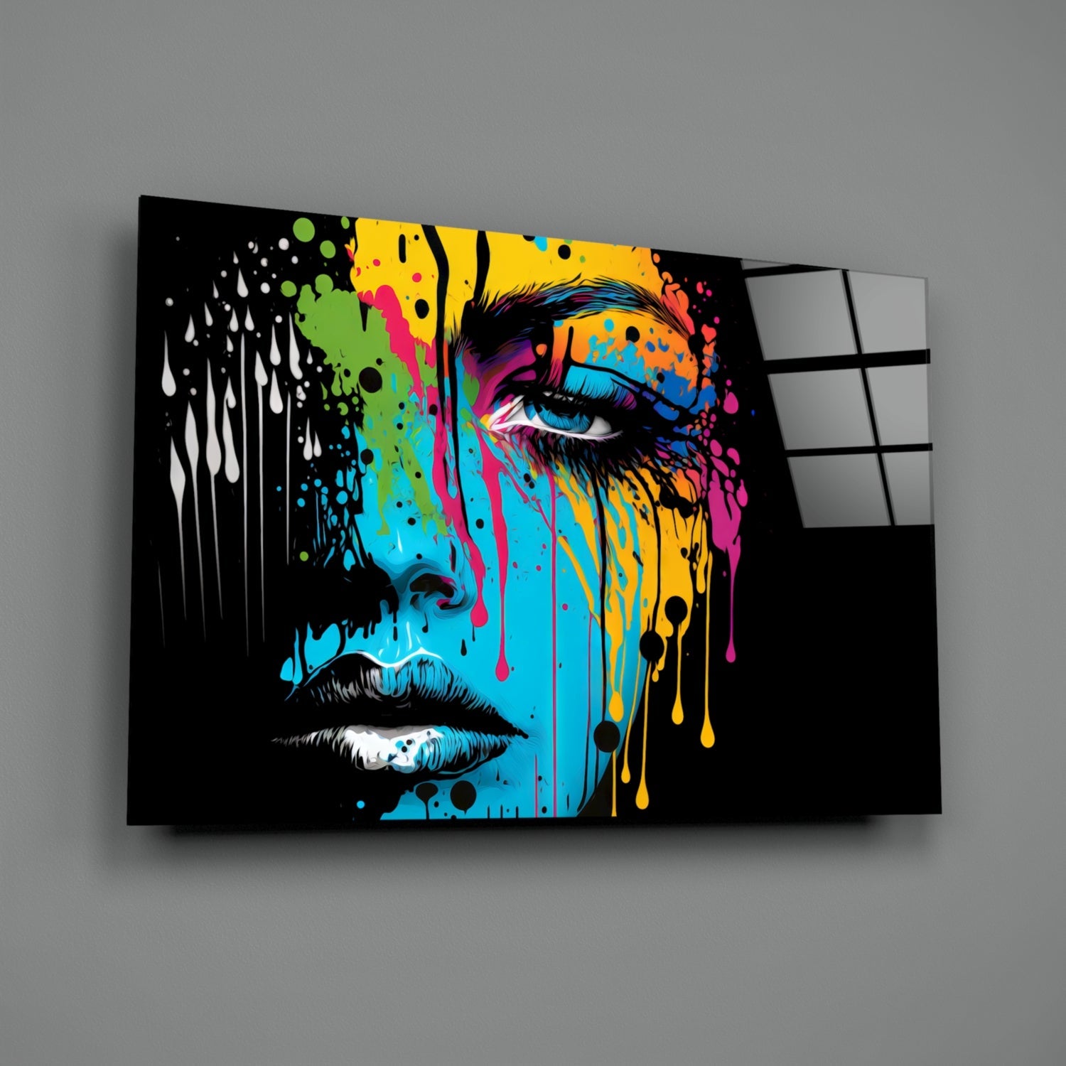 Colorful pop art portrait on black glass panel with vibrant paint drips in yellow, blue, pink, and green, displayed at an angle against gray wall.