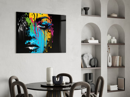 Colorful pop art portrait with blue, yellow, and pink paint drips on black background, displayed above round dining table in modern interior with built-in shelving.