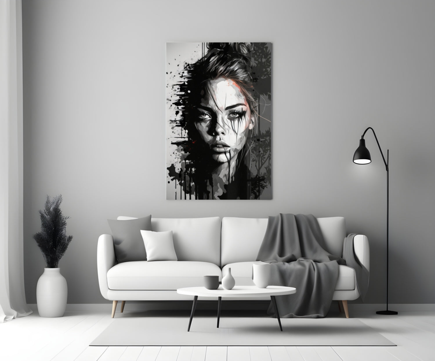 Black and white portrait glass wall art depicting a woman's face with splatter effects, displayed above a white sofa in a minimalist living room.