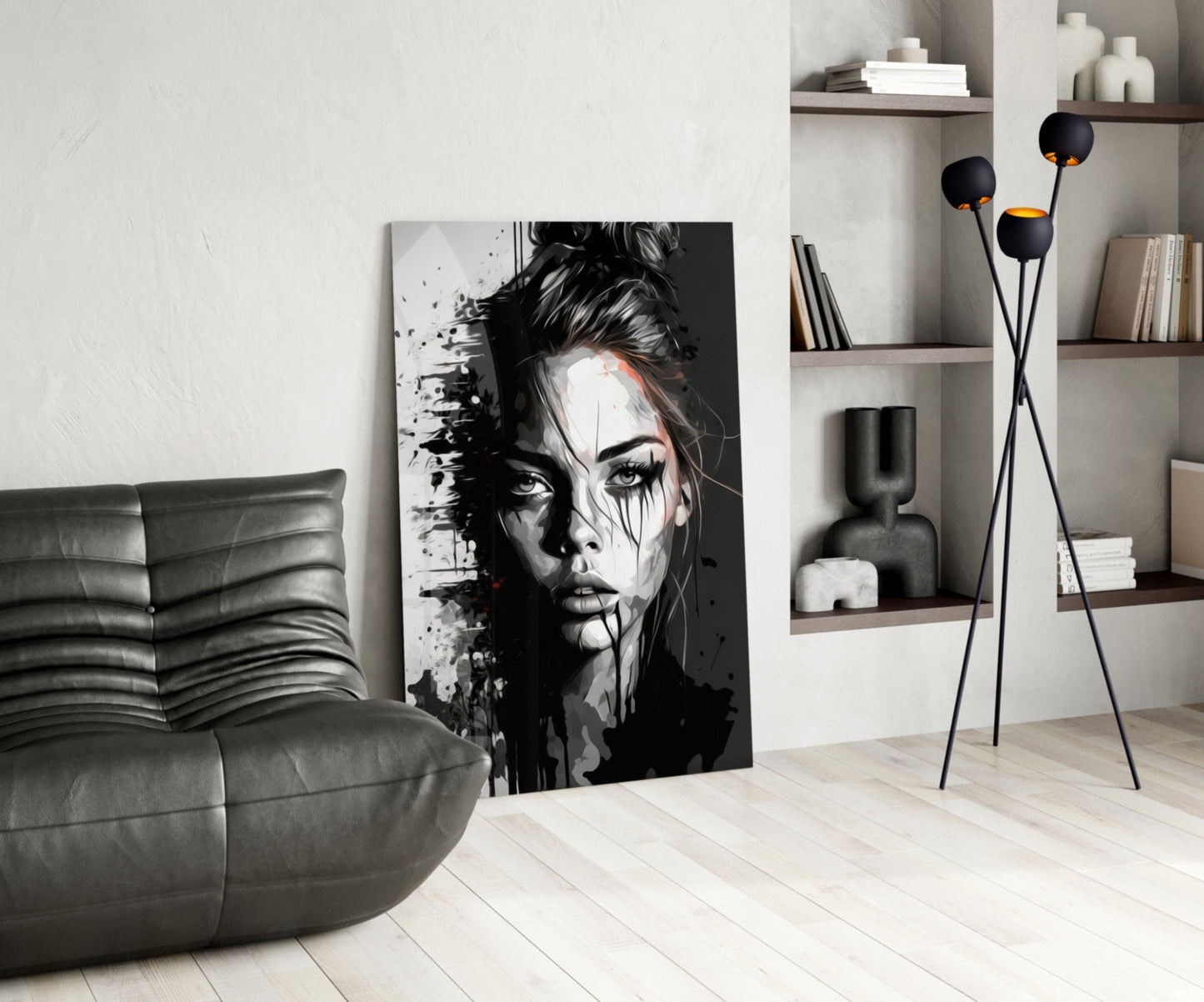 Black and white portrait glass art leaning against wall in modern living room with grey sofa and shelving.